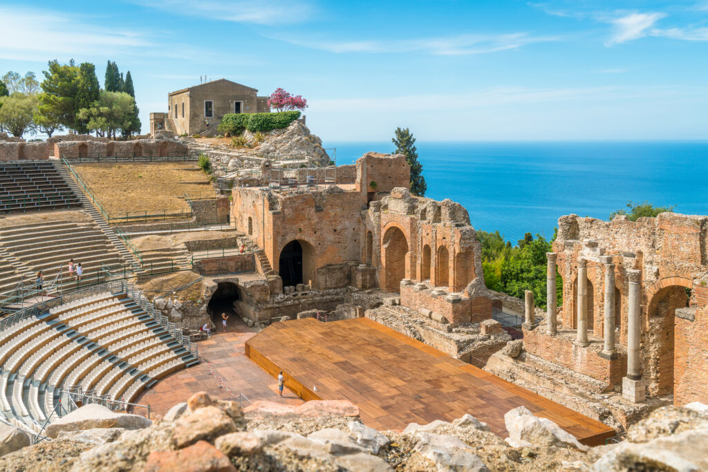Ruins of the ancient Greek theater in Taormina on a sunny summer day with the Mediterranean Sea Messina, Sicily, Italy