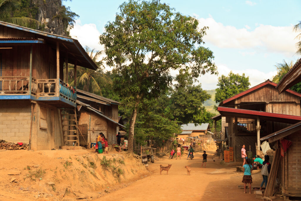 Oudomxay province, Local kids and families are on the street in a local traditional village, typical rural wooden houses in the background, Laos