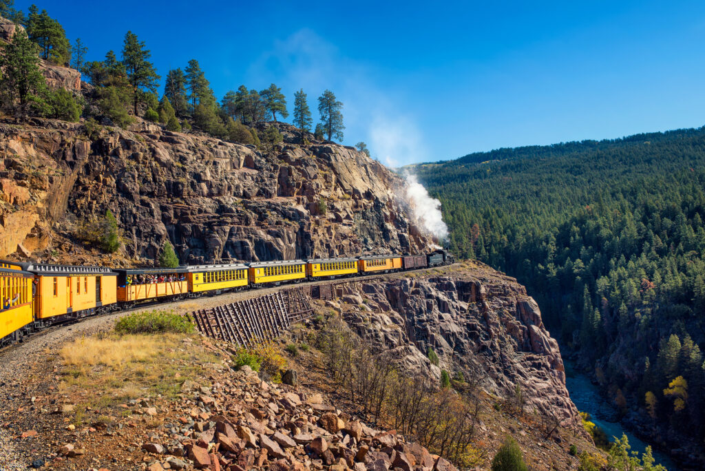 Tourists ride the historic steam engine train from Durango to Silverton through the San Juan Mountains in Colorado, USA