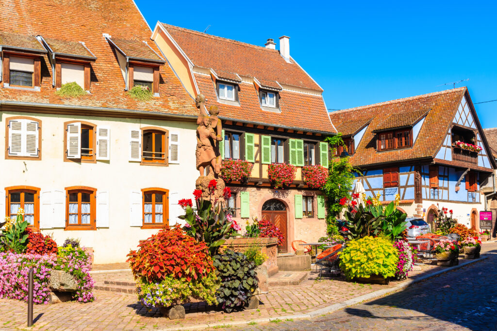 KINTZHEIM VILLAGE, FRANCE - SEP 19, 2019: Colorful houses decorated with flowers on street in beautiful old village of Kintzheim which is located on famous Alsace wine route, France.